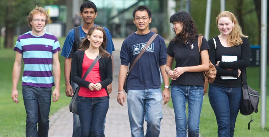 Smiling students walking on ANU campus